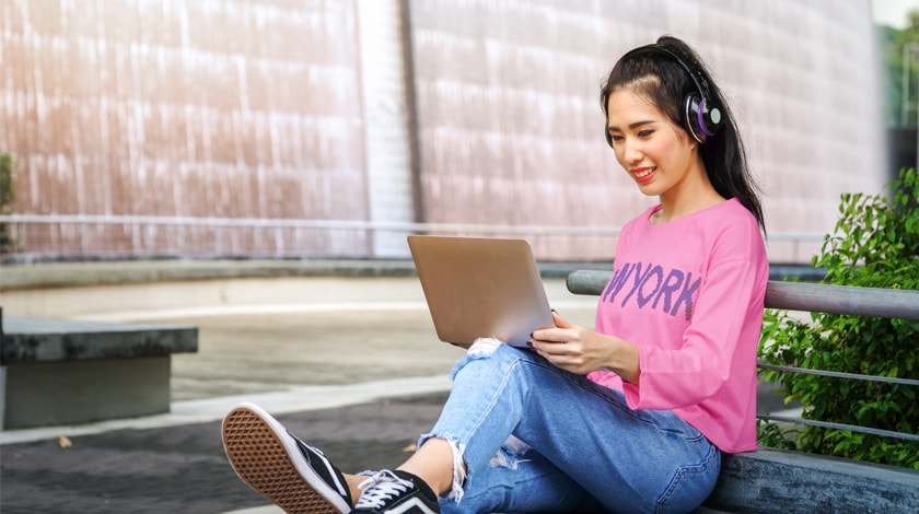 Asian female high school student prepares college application on laptop - Connections Academy