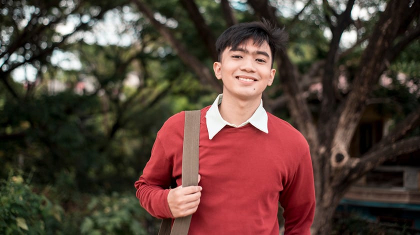 Online high school student with backpack smiling outside