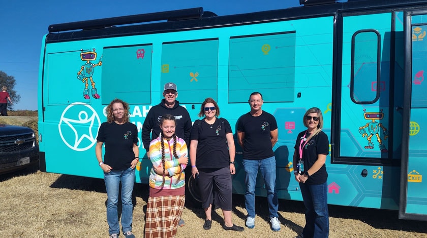 A group of Oklahoma Connections Academy staff and a student standing outside the Mobile STEM Lab Bus